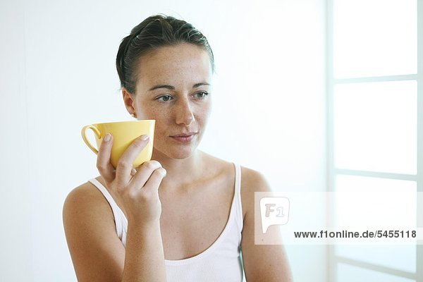 Junge Frau hält Tasse.