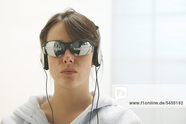 Frau im Bademantel mit Sonnenbrille und Kopfhörern