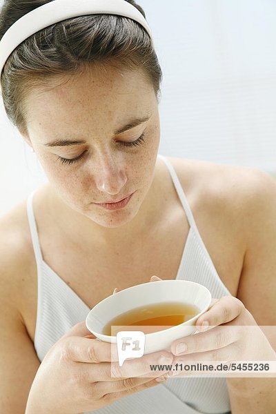 junge Frau hält eine Tasse mit Tee in ihren Händen