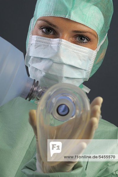 Junge Frau in OP-Kleidung hält eine Beatmungsmaske