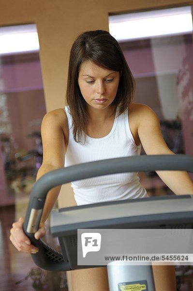Junge Frau im Fitnessstudio auf dem Ergometer