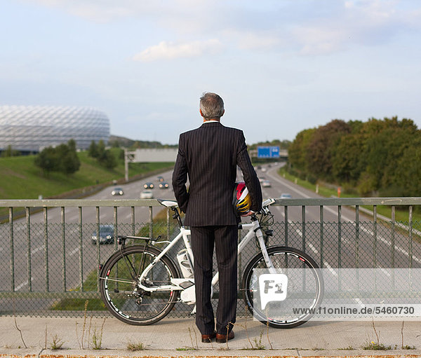 Geschäftsmann mit Fahrrad auf der Brücke