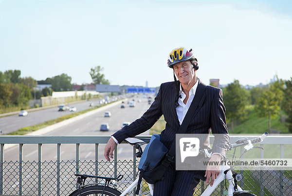 Businessman with bicycle on bridge