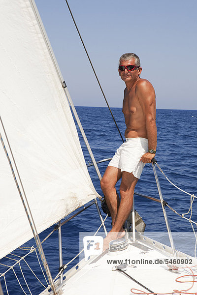 Older man on railing of sailboat