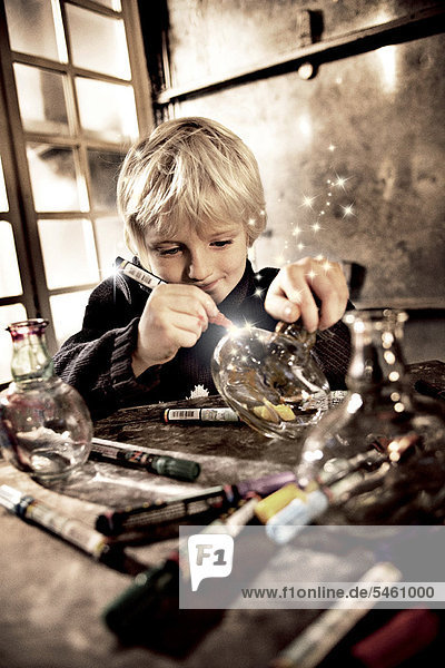 Boy drawing on glass jar with light