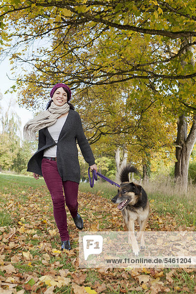 Lächelnde Frau spazieren gehender Hund im Park
