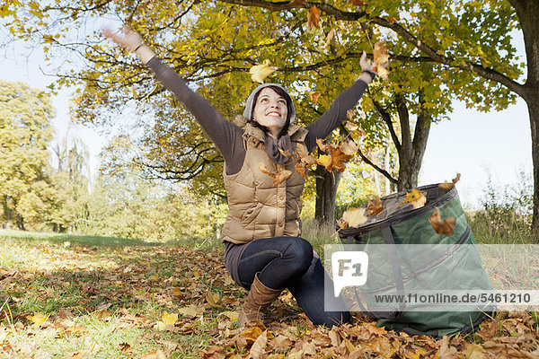 Woman playing with fall leaves in park