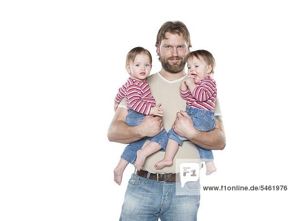 Studio portrait of father holding two baby daughters