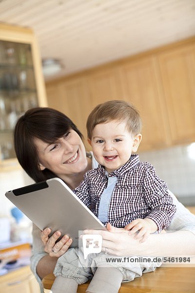 Mother showing digital tablet to baby son