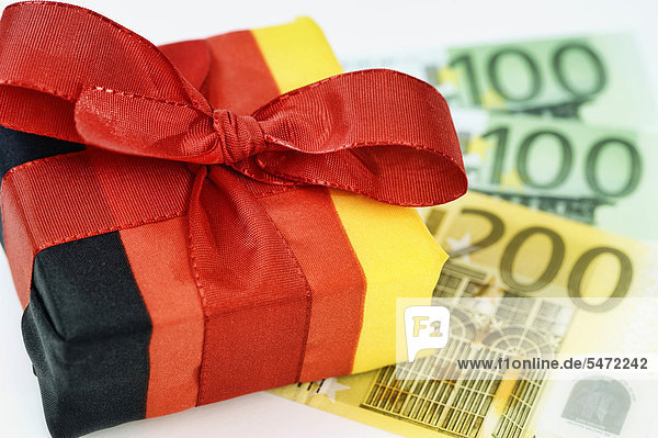 Geschenk in deutschen Nationalfarben  Euro-Geldscheine  Symbolbild Steuersenkung  Steuergeschenk