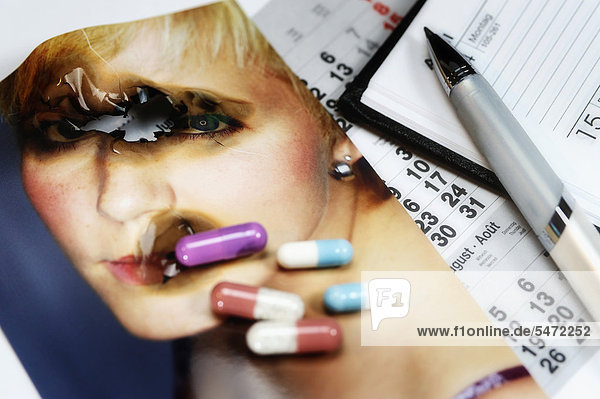 Verbranntes Foto und Tabletten  Kalender  Kugelschreiber  Symbolbild Burnout-Syndrom