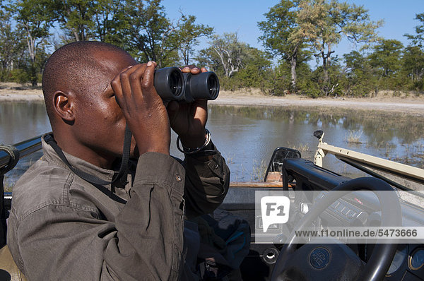 Mann mit Fernglas  Savuti-Kanal  Linyanti  Botsuana  Afrika
