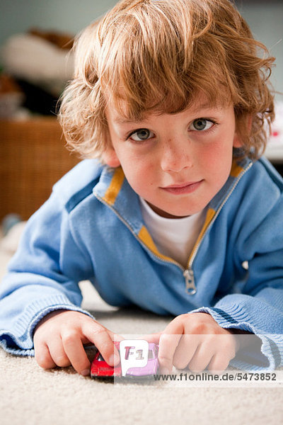 Young boy playing at home with two toy cars