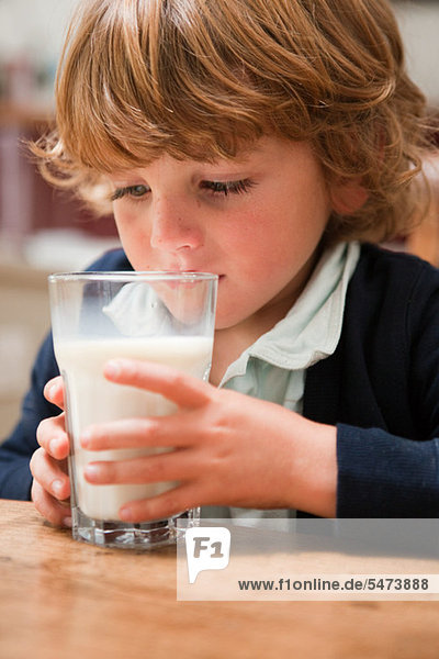 Young boy drinking a large glass of milk