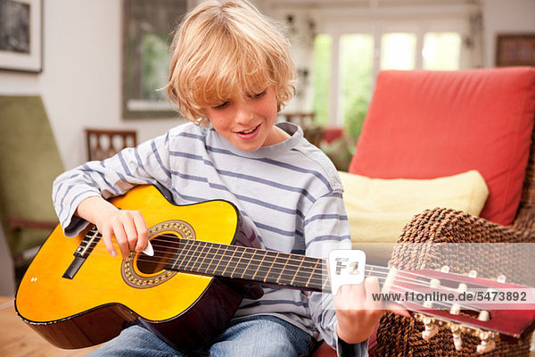 Young boy playing a guitar at home