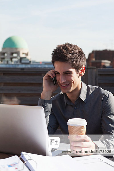Handy Dach benutzen Mann Notebook Kurznachricht Kaffee multitasking
