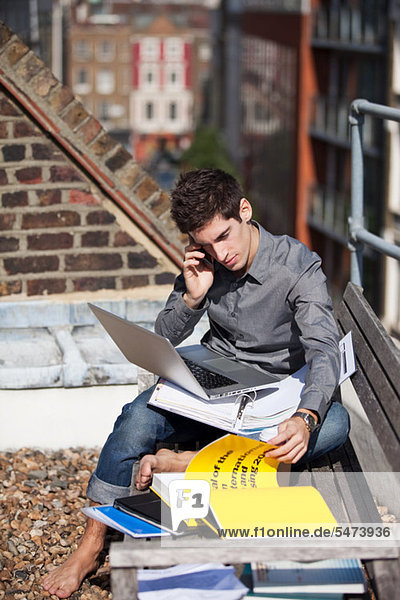 Junger Mann bei der Arbeit mit einem Laptop auf dem Dach