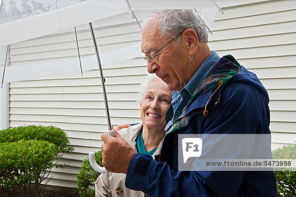 Senior Couple Holding Regenschirm außerhalb