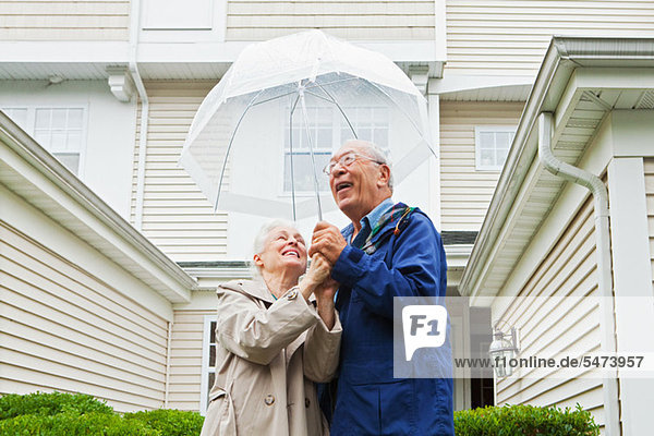Senior Couple Holding Regenschirm außerhalb
