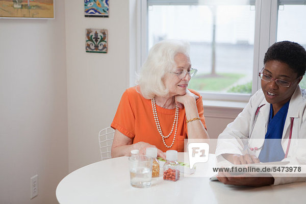 Senior Woman und Arzt mit Computer Tablet am Tisch