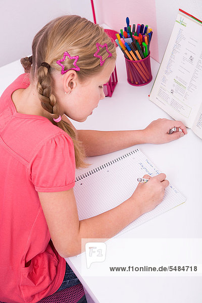Young schoolgirl doing her homework at her desk