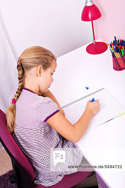Young schoolgirl doing her homework at her desk