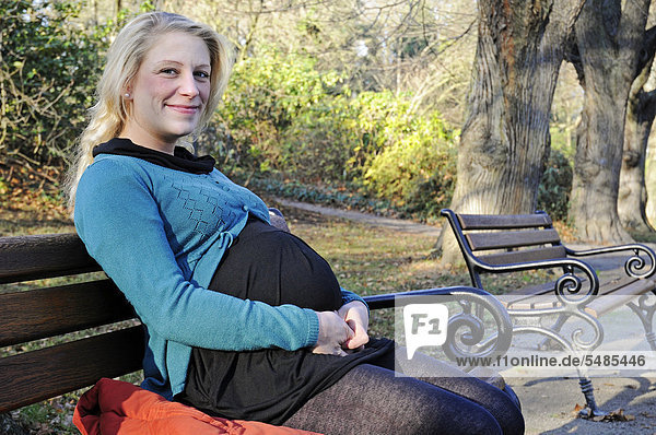 Schwangere Frau  30 Jahre  sitzt auf einer Parkbank  Dortmund  Nordrhein-Westfalen  Deutschland  Europa  ÖffentlicherGrund Schwangere Frau
