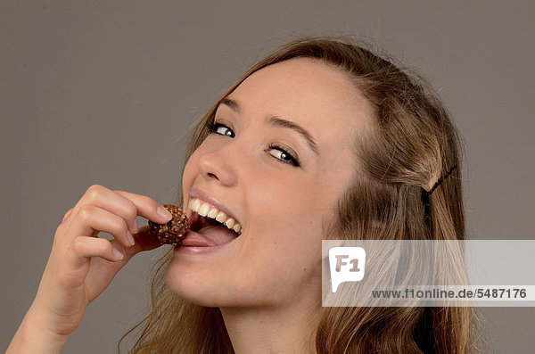 Junge Frau isst eine Schokoladenkugel