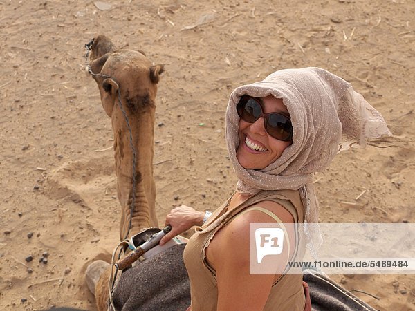 Marokko  Merzouga  Reife Frau auf dem Kamel in der Wüste Erg Chebbi
