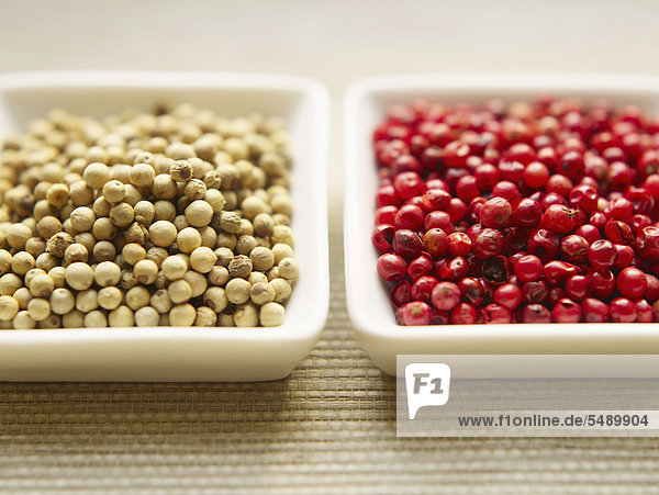 White and pink peppercorn in bowls  close up