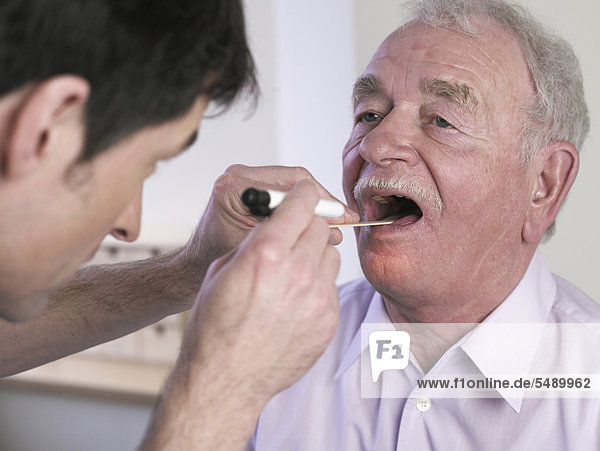 Deutschland  Hamburg  Arzt untersucht Patient mit Zungenspatel