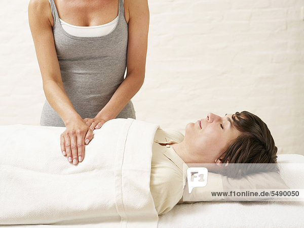 Woman receiving reiki treatment from masseur