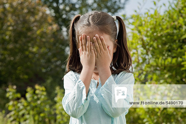 Girl playing hide and seek in garden