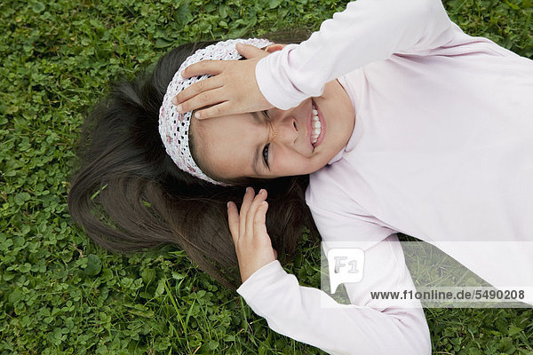 Mädchen auf Gras im Garten liegend  lächelnd  Portrait