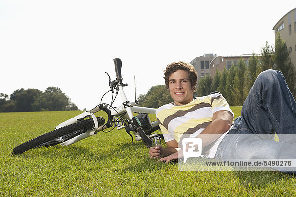Junger Mann im Gras liegend  lächelnd  Portrait