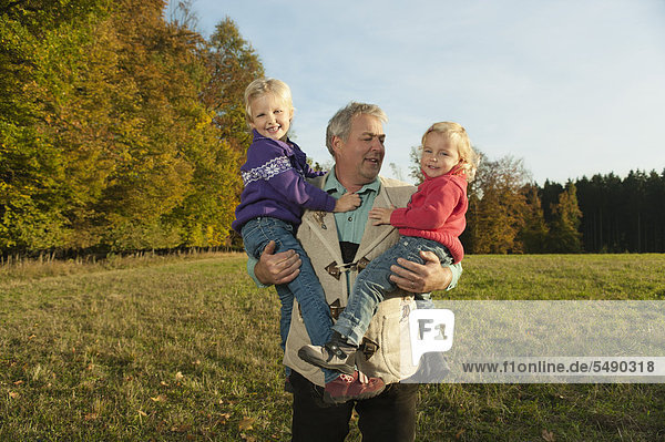 Germany  Bavaria  Grandfather with granddaughters during autumn  smiling