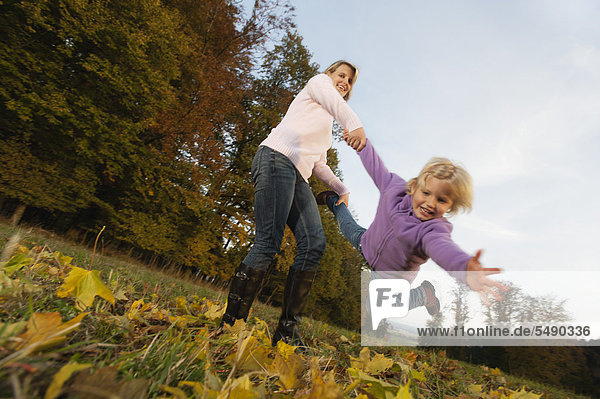 Deutschland  Bayern  Mutter und Tochter spielen im Herbst