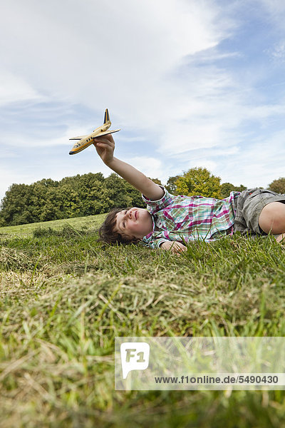 Junge spielt mit Modellflugzeug im Park
