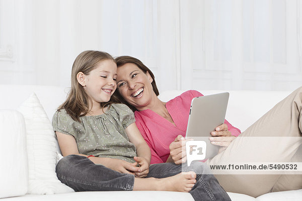 Germany  Munich  Mother and daughter using digital tablet  smiling