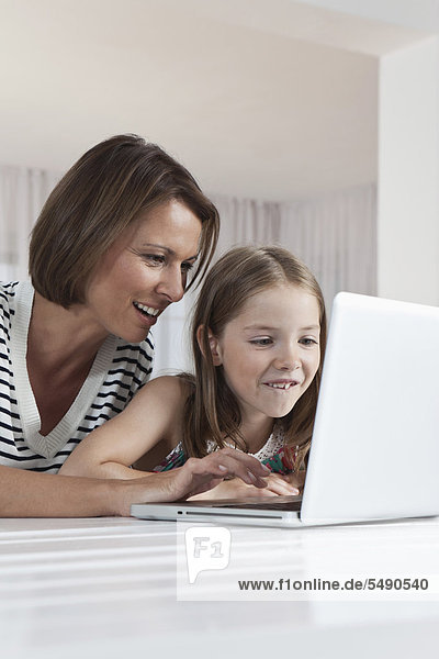 Germany  Munich  Mother and daughter using laptop  smiling