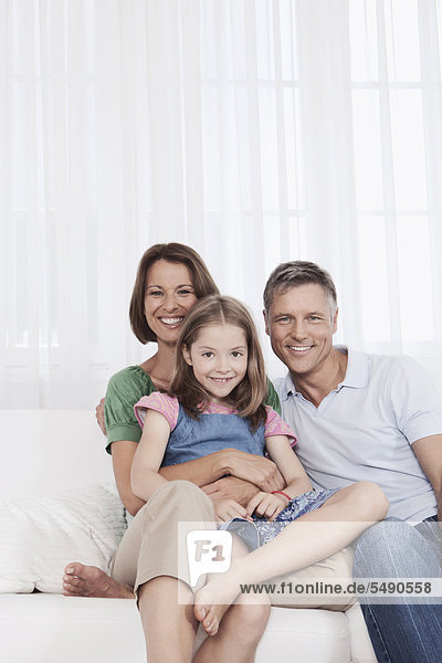Deutschland  München  Familie auf Couch sitzend  lächelnd  Portrait