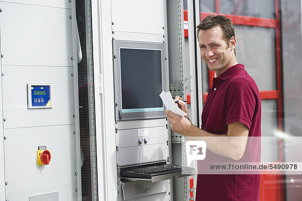 Deutschland  München  Techniker beim Schaltschrank stehend  lächelnd  Portrait
