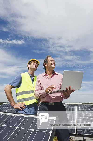 Germany  Munich  Engineers with laptop in solar plant
