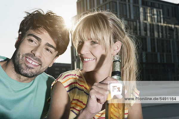 Deutschland  Köln  Junges Paar mit Bierflasche  lächelnd