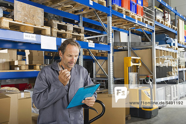 Germany  Bavaria  Munich  Manual worker checking list in warehouse