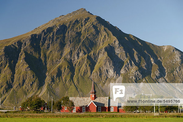 Die rote Stabkirche von Flakstad vor steilen Bergen  Vareid  Fredvang  Insel Flakstad¯ya  Flakstadoya  Lofoten  Nordland  Norwegen  Europa