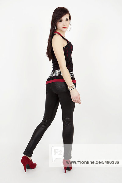 Junge Frau mit schwarzem Top  Lack-Leggins und roten High Heels posiert als Pin up Girl