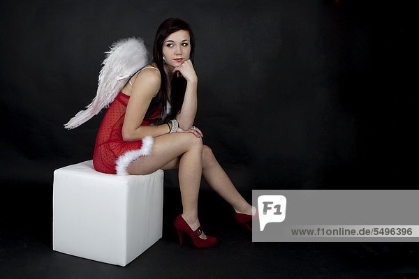Young woman posing in red Christmas lingerie with angel wings