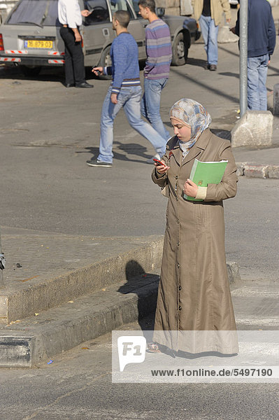 Street scene  Palestinian woman wearing a head scarf holding a mobile phone  Jerusalem  Israel  Middle East