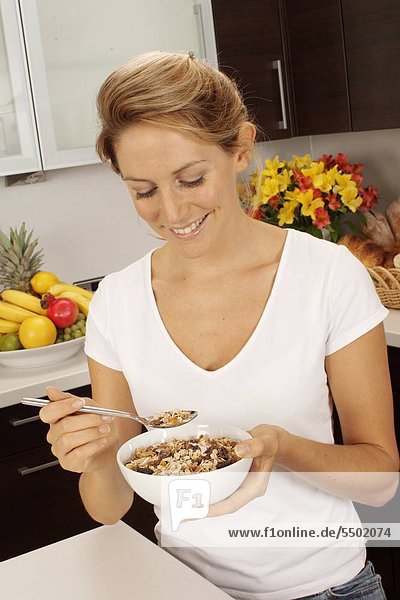 Woman In Kitchen Eating Bowl von Müsli